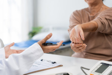 Doctor engaging with an elderly patient displaying wrist discomfort during a medical consultation at a healthcare clinic