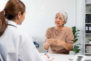 Fototapeta premium Senior patient discussing health concerns with female doctor in a clinic, receiving medical advice and support