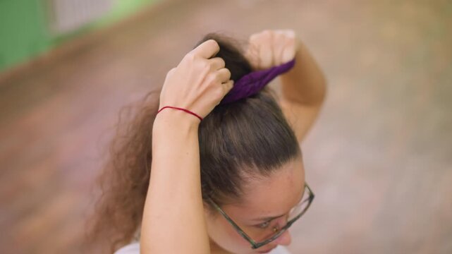 Close view of woman packing hair with hair packer hands gathering strands securing style under soft studio light blurred background intimate grooming motion showing texture movement confident focused