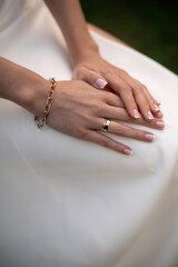Elegant Hands with Gold Jewelry on White Dress