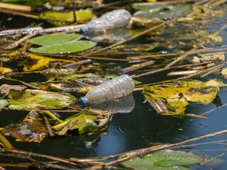 Floating white garbage plastic bottles in the pond