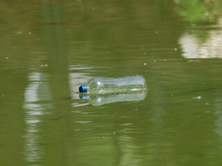Floating white garbage plastic bottles in the pond