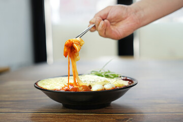 치즈 폭탄 떡볶이를 젓가락으로 한 점 집은 모습을촬영하였습니다.