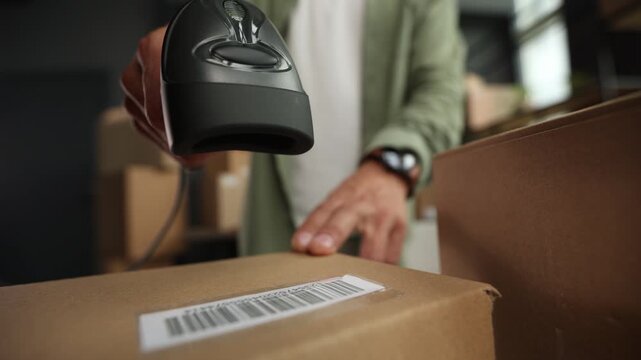 A person is holding a black and silver barcode scanner
