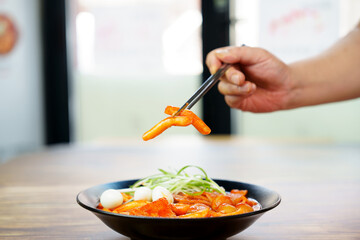 떡볶이를 젓가락으로 한 점 들고 있는 모습입니다.