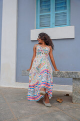 A woman is sitting on a bench wearing a colorful dress