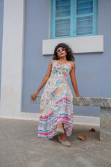 A woman is wearing a colorful dress and is sitting on a bench