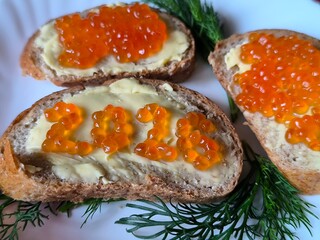 sandwich with butter and red caviar. The numbers 2026. A white plate on a red background. Dill sprigs. 2026 made from caviar on a sandwich.