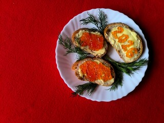 sandwich with butter and red caviar. The numbers 2026. A white plate on a red background. Dill sprigs. 2026 made from caviar on a sandwich.