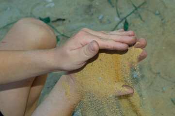 close-up - a boy is playing with sand, sand is pouring out of his hands