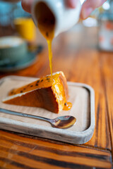 Cheesecake slice with passion fruit sauce being poured on top