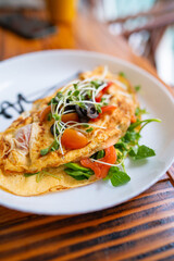 Omelet with fresh vegetables and sprouts on plate