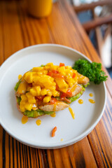 Closeup grilled chicken avocado toast with mango salsa and parsley