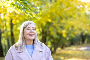 Senior woman enjoying autumn day in park smiling