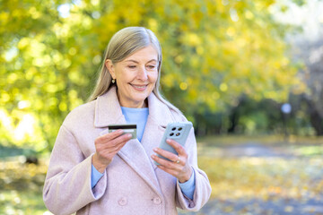 Senior woman doing online shopping with credit card and phone outdoors