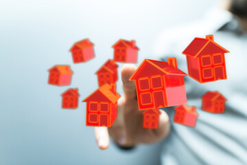 Conceptual image showing hand pointing at floating houses, symbolizing housing, real estate, dream homes, and property ownership.