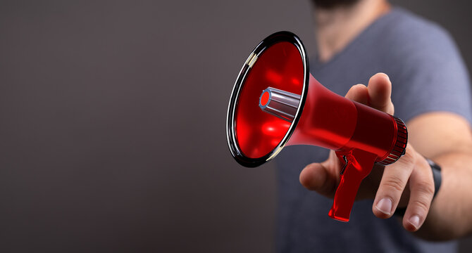 A man holds a red megaphone towards the viewer, symbolizing announcement, communication, and reaching out. Great for marketing, news or sharing