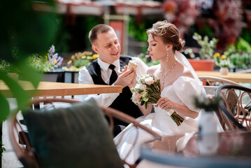 Happy newlyweds eat ice cream at a street cafe on their wedding day.