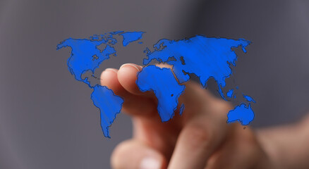 A person's finger touching a blue world map on a gray background, symbolizing global interaction, connection, and travel. Represents concepts li