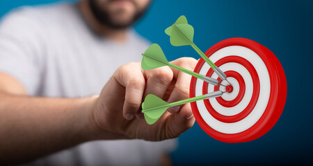 Close up of a hand holding darts that have hit the center of a target, representing success and...