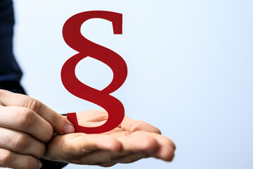 Image of a red paragraph symbol held in hands, perfect for legal, justice, and law concepts.  High-quality stock photo.