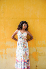 Fototapeta premium A woman in a white dress stands in front of a yellow wall