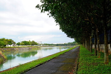 Scenic lakeside walking path with tree-lined sidewalk, peaceful atmosphere and romantic natural landscape. Serene outdoor setting ideal for relaxation and nature walks.