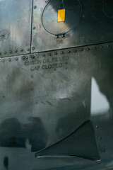 Airplane Engine Detail with “Check Oil Filled Cap Closed” Text. Macro shot of airplane engine surface. Close-up view showing metallic texture and industrial details of aviation engineering.