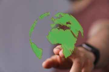 A hand gently interacts with a vibrant green digital globe, symbolizing global connection,...