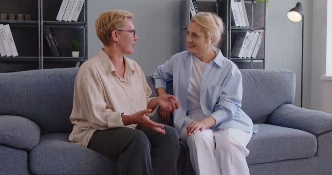 Senior woman mother talking with daughter sitting on sofa at home show support and empathy in conversation together. Family trust, care, love and relationship. Core concept support and trust.