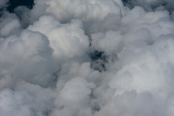 View of White Clouds from Airplane Window. Beautiful aerial view of soft white clouds from an airplane window during flight. The peaceful atmosphere of the sky above the clouds.