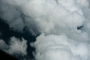 View of White Clouds from Airplane Window. Beautiful aerial view of soft white clouds from an airplane window during flight. The peaceful atmosphere of the sky above the clouds.