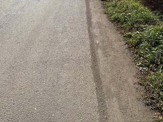asphalt road edge with grass and soil border