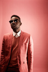 Studio portrait of young African American hipster man in stylish smart pink suit, shirt, knit...