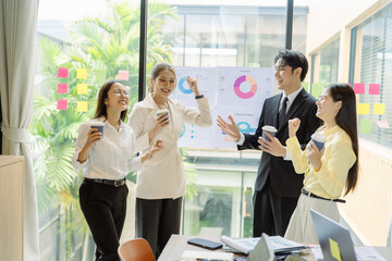 Group of people celebrating in front of whiteboard with graph. Creative young Asian business team. Colleagues in office. Happy with success.