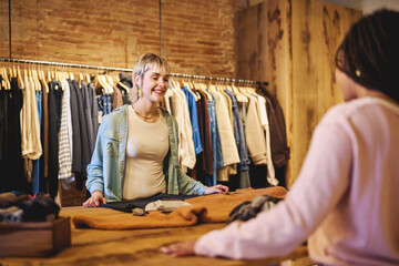 Fototapeta premium Young woman smiling at boutique counter during shopping experience