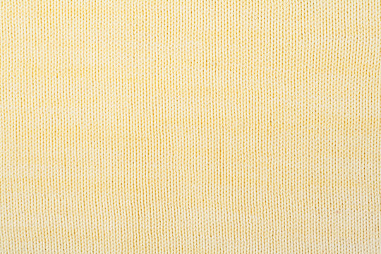 Sweater or scarf fabric texture large knitting. Knitted jersey background with a relief pattern. Wool hand- machine, handmade, yellow.