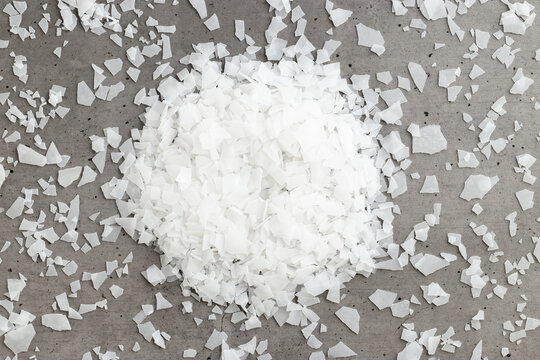 Top view heap of Magnesium Salt Flakes on grey background, detailed white particles sea salt, natural pattern Magnesium therapy, Health Benefits, self-care, promoting wellness, home relaxation spa