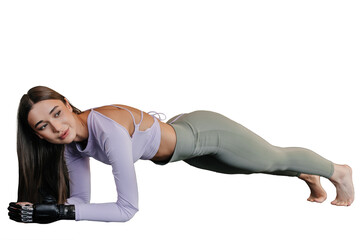 Beautiful brunette caucasian girl in sportswear with bionic hand makes plank exercises on...