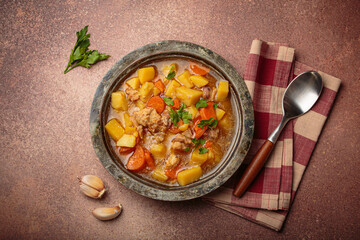 Hot chicken stew or soup with tender chicken pieces, chunky potatoes, and vibrant carrots garnished with fresh parsley in rustic bowl, comfort food for autumn and winter