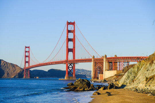 The Golden Gate Bridge viewed from the western side during dusk from Marshalls Beach with the beach and coast in the foreground.