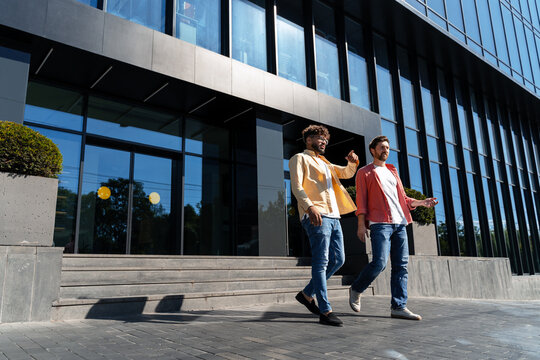 Diverse men walking and talking near office building