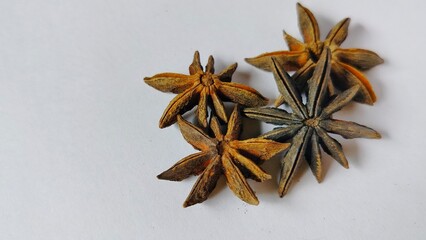 a charming close-up of a number of dried star anise, beautifully scattered on a clean white background