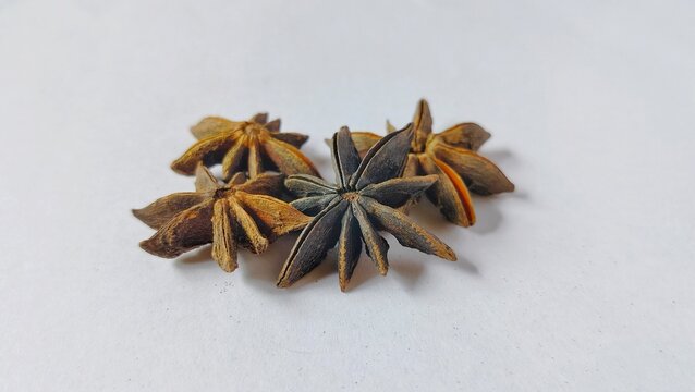 a charming close-up of a number of dried star anise, beautifully scattered on a clean white background