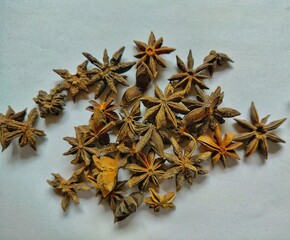a charming close-up of a number of dried star anise, beautifully scattered on a clean white background