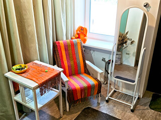 Cozy corner with a colorful chair, table, and mirror in a well-lit room