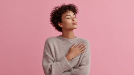 Young woman expressing heartfelt gratitude, eyes closed, hands on chest, pink studio background, indoor concept