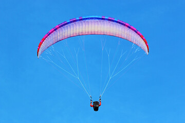 	
Paraglider flying in a blue sky	