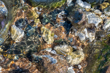 Gentle water ripples dancing over flint stones in tidal pool