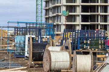 Large wooden cable spools with black and white electrical wires, construction material storage, utility infrastructure supply, job site logistics and power distribution